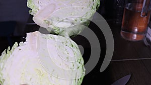 Woman cuts and chops white cabbage with a knife in the kitchen