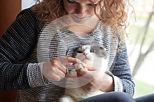A woman cuts the claws of a cat with nail scissors, pet care