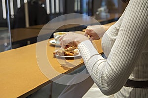 Woman cuts croissant and drinks coffee at a table in a cafe