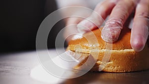 Woman cuts fresh bun to make hamburger on table closeup