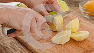 Woman cuts fresh peeled apples on a wooden cutting board