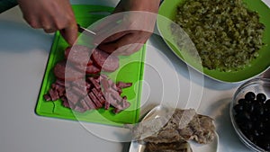 The woman cuts meat into pieces. Soup saltwort. Ingredients for cooking are on the table.