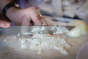 Woman cuts onions on a white plastic board
