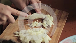 Woman cuts onions on a wooden board