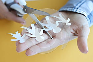 Woman cuts paper figures of family with scissors closeup