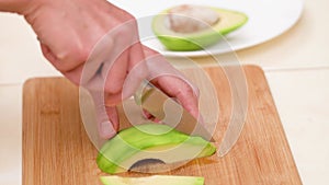 Woman cuts peeled avocado on slices. Cutting an avocado in pieces. Preparing healthy food. Healthy vegan eating.
