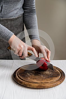 Woman cuts red apple on board close