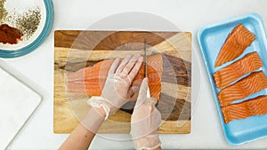 Woman cuts salmon on wooden cutting board.