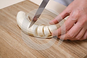 Woman cutting banana into slices close-up of hands