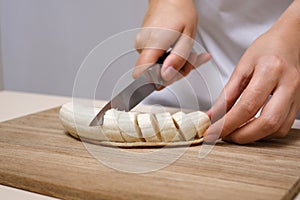 Woman cutting banana into slices close-up of hands