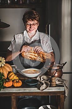 Woman cutting bread for Autumn seasonal pumpkin cream soup