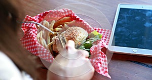 Woman cutting burger with fork and knife in a restaurant