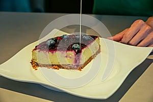A woman cutting a delicious blueberr cheesecake in a coffee shop