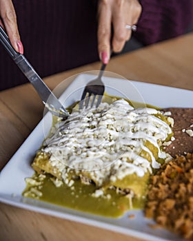 Woman cutting into an Enchilada tortilla on a wooden table
