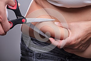 Woman Cutting The Excessive Belly Fat With Scissor