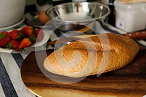 woman cutting french bread on a wooden cutting board for breakfast