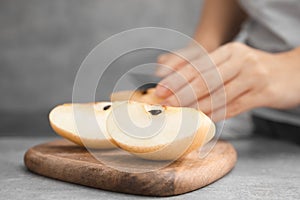 Woman cutting fresh apple pear at grey table, focus on fruit