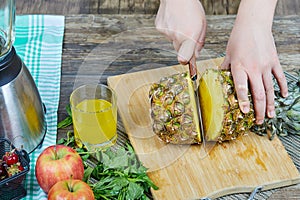 Woman cutting a fresh pineapple on a wooden cutting board