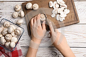 Woman cutting fresh raw mushrooms on table, top view