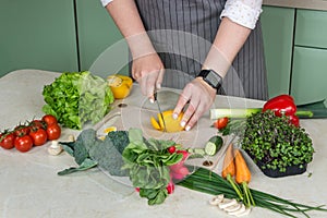Woman cutting fresh vegetables for salad in kitchen