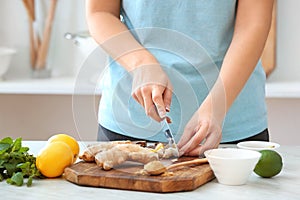 Woman cutting ginger on table in kitchen