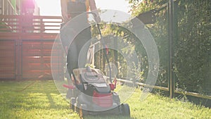 Woman cutting grass with corded electric lawn mower