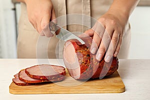 Woman cutting ham at table in kitchen