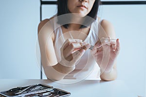 Woman cutting nails with nail clipper,Female using tweezers clipping hes fingernails