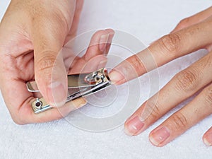 Woman cutting nails using nail clipper on white background. heal