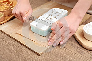 Woman cutting natural handmade soap on table, closeup