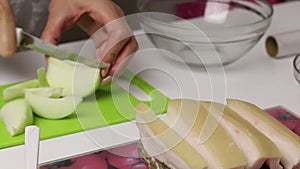 The woman is cutting the onion. The chopped fat lies on the board. Container contains parsley and garlic. Salted lard with herbs