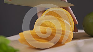 Woman cutting orange with a knife on a kitchen table. Woman making orange fresh juice.