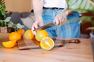 Woman cutting oranges in a kitchen full of plants.