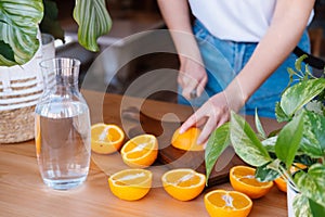 Woman cutting oranges in a kitchen full of plants.