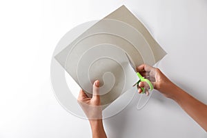 Woman cutting paper with scissors on white background, top view