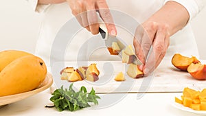 Woman cutting peach. Close up view, white background