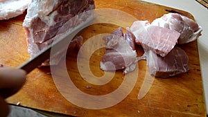 Woman cutting raw beef meat on a cutting board for cooking stew or goulash