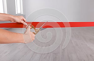 Woman cutting red ribbon on blurred background