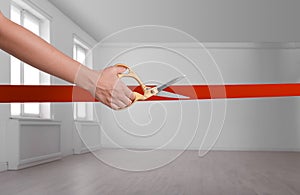 Woman cutting red ribbon on blurred background