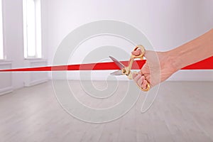 Woman cutting red ribbon on blurred background