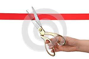 Woman cutting red ribbon with scissors on white background