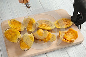 Woman cutting ripe cactus pear on wooden board