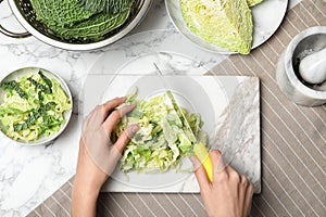 Woman cutting savoy cabbage on marble board