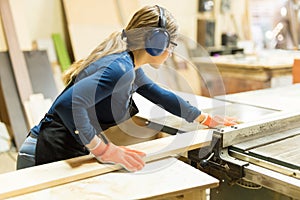 Woman cutting some wood with a table saw