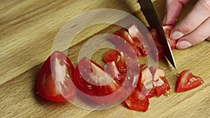 Woman cutting tomato with knife on a wooden board. slow motion