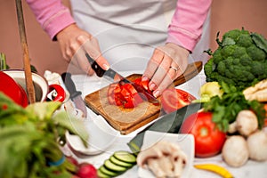 Woman cutting tomato on slices on chopping board