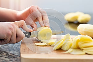 woman cutting up potatoes on a cutting board