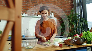 Woman cutting vegetables for salad in kitchen. Housewife cooking healthy meal.