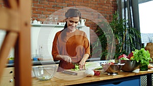 Woman cutting vegetables for salad in kitchen. Housewife cooking healthy meal.