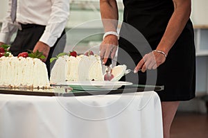 woman cutting wedding cake in reception room